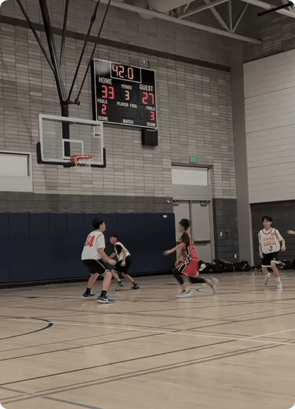 Youth basketball players on court under the scoreboard